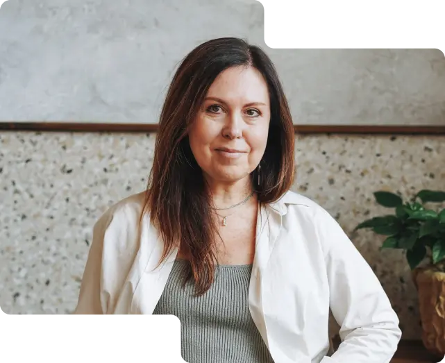 Contented customer photo showcasing a poised woman with shoulder-length hair and a subtle smile, wearing a white jacket over a green top, indicative of the diverse clientele who trust our cryptocurrency exchange services.